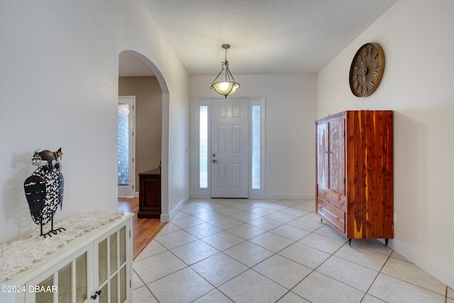 foyer entrance featuring a textured ceiling and light tile patterned floors