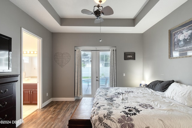 bedroom with ensuite bath, access to exterior, hardwood / wood-style flooring, a tray ceiling, and ceiling fan