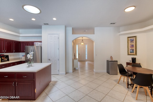 kitchen with stainless steel fridge, light tile patterned floors, and a center island