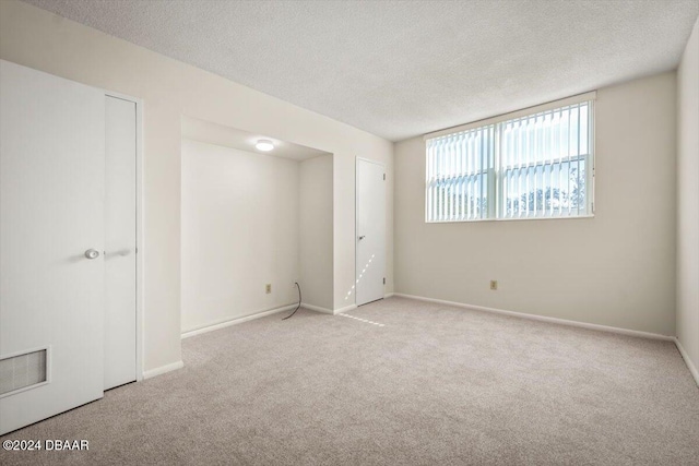 carpeted empty room featuring a textured ceiling