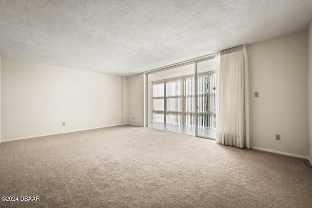 carpeted empty room featuring a textured ceiling