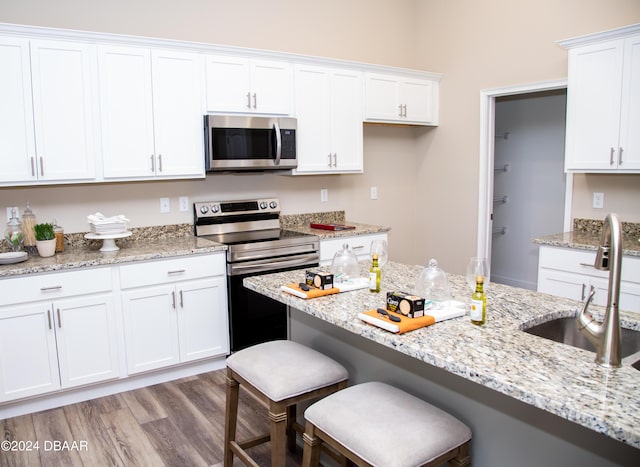 kitchen with a sink, appliances with stainless steel finishes, a breakfast bar, and white cabinets