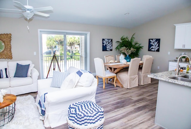 living area featuring vaulted ceiling, a ceiling fan, and light wood finished floors