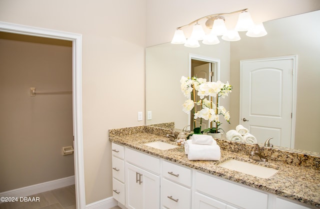 full bath with double vanity, baseboards, and a sink