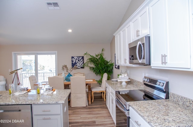 kitchen featuring visible vents, light wood-type flooring, light stone counters, stainless steel appliances, and white cabinetry