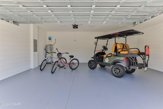 garage with concrete block wall, electric panel, and a garage door opener