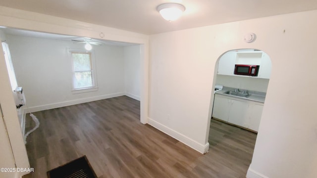 unfurnished room with ceiling fan, dark wood-type flooring, and sink