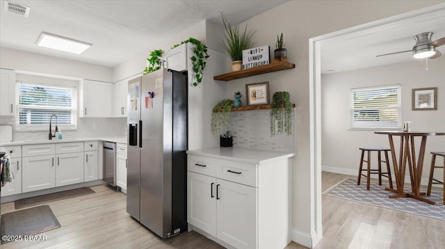 kitchen featuring visible vents, light wood-style floors, white cabinets, stainless steel appliances, and open shelves