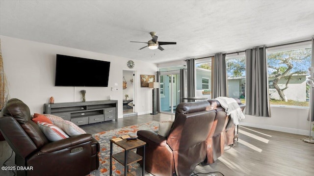 living area featuring wood finished floors, a healthy amount of sunlight, baseboards, and ceiling fan