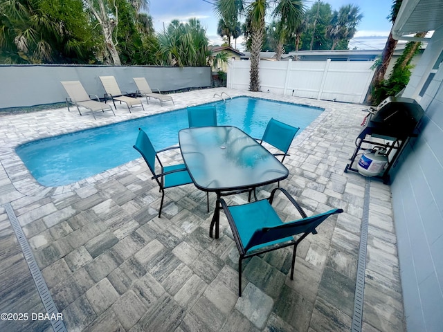 view of pool featuring a patio area, area for grilling, a fenced in pool, and a fenced backyard