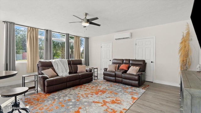 living room featuring baseboards, wood finished floors, a ceiling fan, and a wall mounted AC