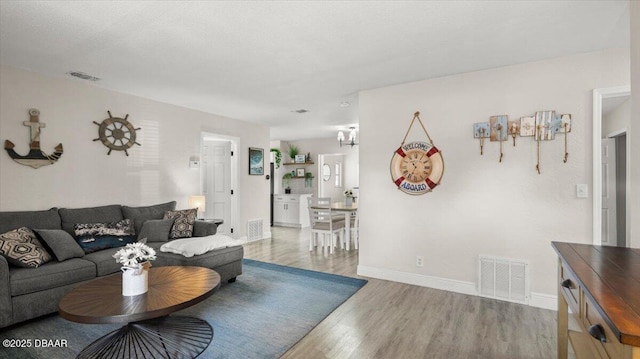 living area with visible vents, baseboards, and wood finished floors