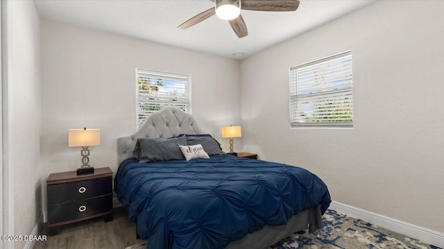 bedroom with multiple windows, wood finished floors, baseboards, and ceiling fan