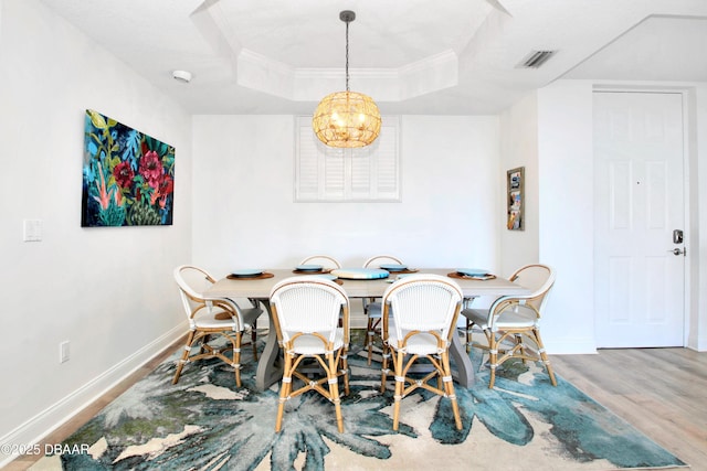 dining room featuring crown molding, a tray ceiling, and hardwood / wood-style flooring