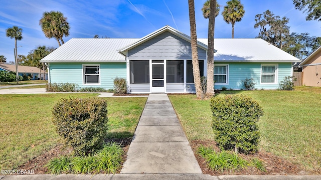 view of front of home with a sunroom, metal roof, and a front lawn