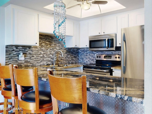 2101 N Atlantic Ave Unit 24, Daytona Beach, FL 32118 - kitchen featuring white cabinets, decorative backsplash, stainless steel appliances, and ceiling fan