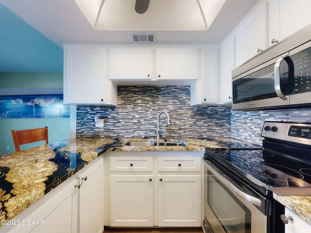 2101 N Atlantic Ave Unit 24, Daytona Beach, FL 32118 - kitchen with visible vents, a sink, white cabinetry, tasteful backsplash, and appliances with stainless steel finishes