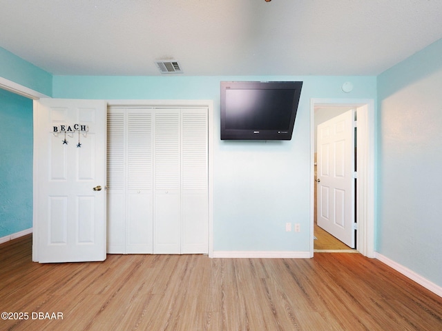 2101 N Atlantic Ave Unit 24, Daytona Beach, FL 32118 - unfurnished bedroom featuring a closet, baseboards, visible vents, and light wood-style floors