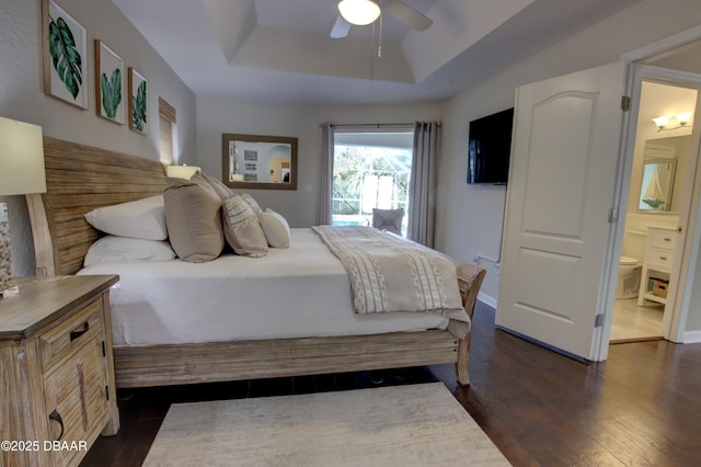 bedroom featuring a tray ceiling, dark hardwood / wood-style floors, ceiling fan, and ensuite bathroom