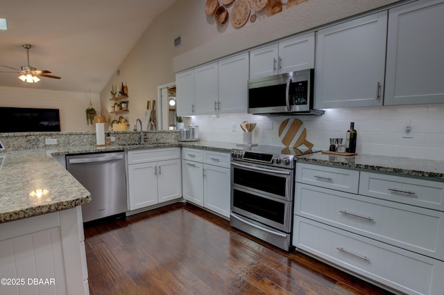 kitchen featuring appliances with stainless steel finishes, lofted ceiling, sink, white cabinets, and kitchen peninsula