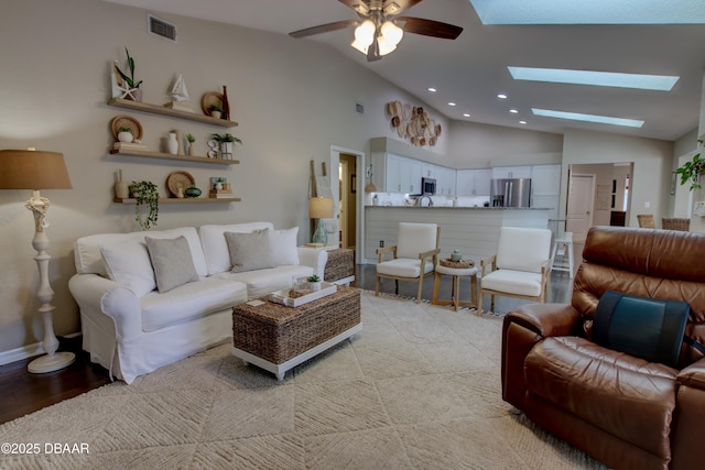 living room with high vaulted ceiling, ceiling fan, and a skylight