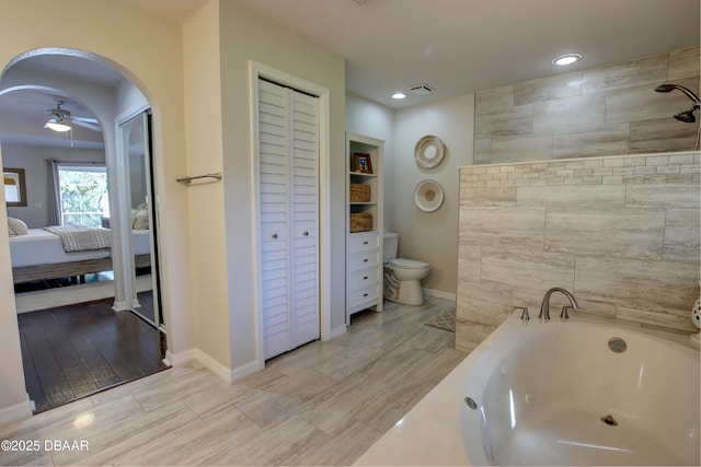 bathroom with a bath, toilet, and ceiling fan