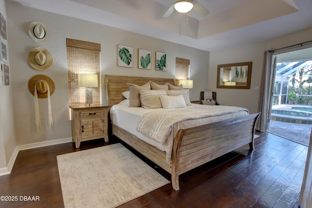 bedroom with dark hardwood / wood-style flooring, access to exterior, a raised ceiling, and ceiling fan