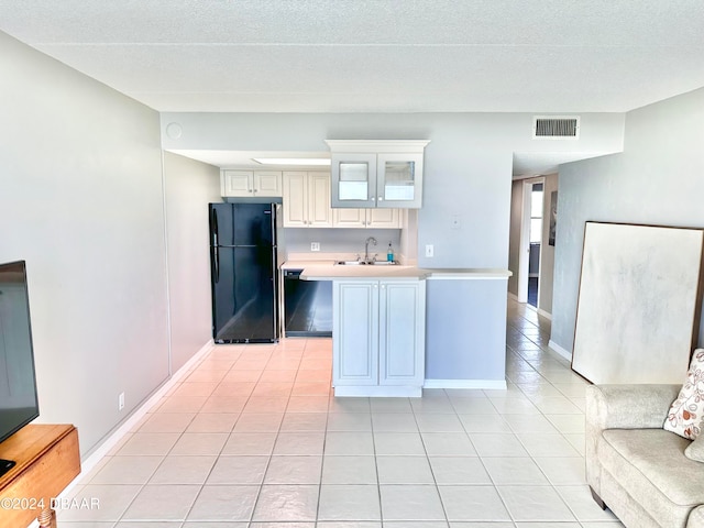 kitchen with light tile patterned flooring, black refrigerator, and a textured ceiling