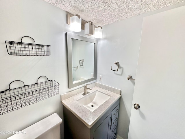 bathroom featuring vanity, a textured ceiling, and toilet