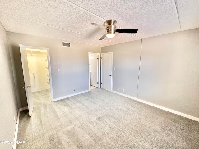 unfurnished bedroom featuring a textured ceiling, light carpet, ceiling fan, and a closet