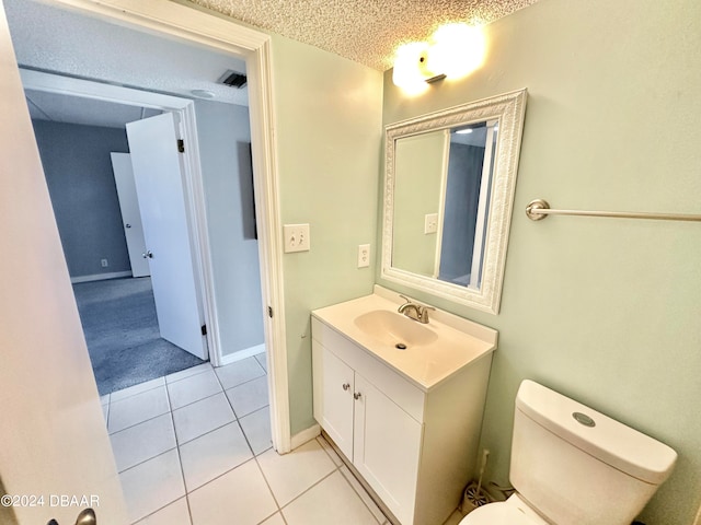 bathroom with toilet, vanity, a textured ceiling, and tile patterned floors