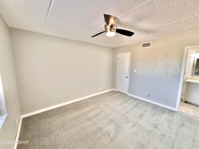 unfurnished bedroom with ceiling fan, a textured ceiling, and light colored carpet