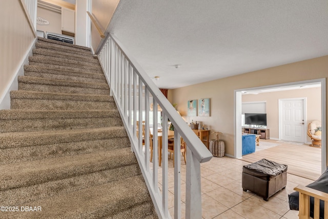 stairs with tile patterned floors and a textured ceiling