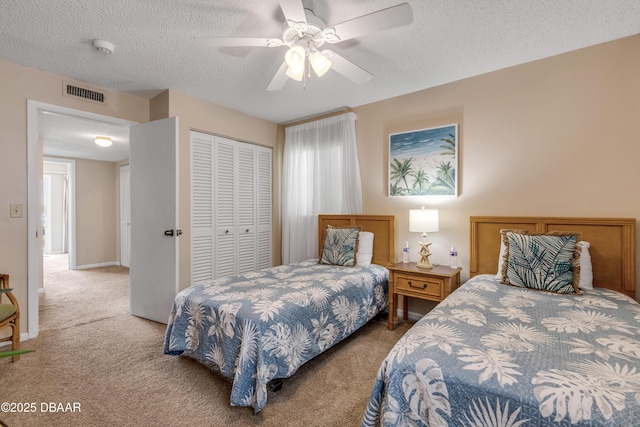 carpeted bedroom with ceiling fan, a closet, and a textured ceiling