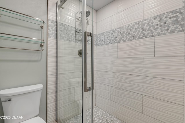 bathroom featuring toilet and a shower with shower door