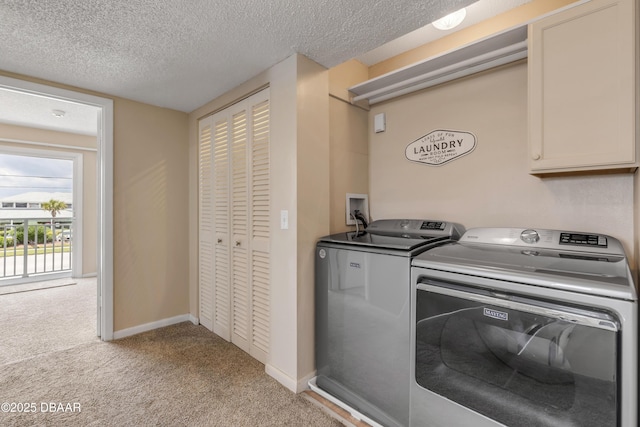 clothes washing area featuring washer and dryer, a textured ceiling, light colored carpet, and cabinets