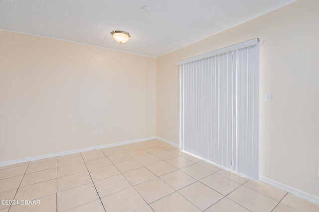 tiled spare room with a textured ceiling and ornamental molding