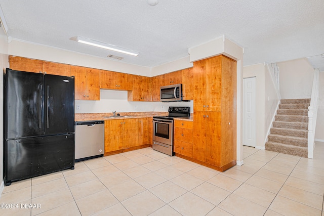 kitchen with appliances with stainless steel finishes, a textured ceiling, and light tile patterned floors