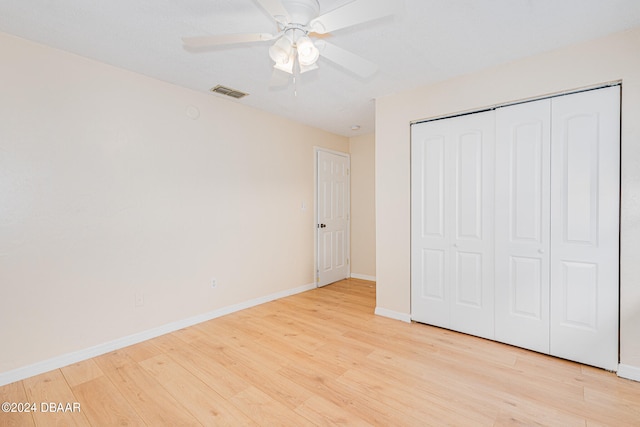 unfurnished bedroom with light hardwood / wood-style floors, ceiling fan, and a closet