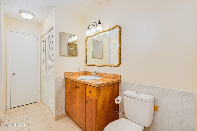 bathroom with toilet, tile walls, a textured ceiling, and tile patterned flooring