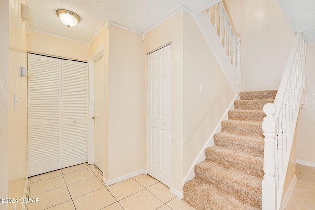 stairway with tile patterned floors, a textured ceiling, and ornamental molding