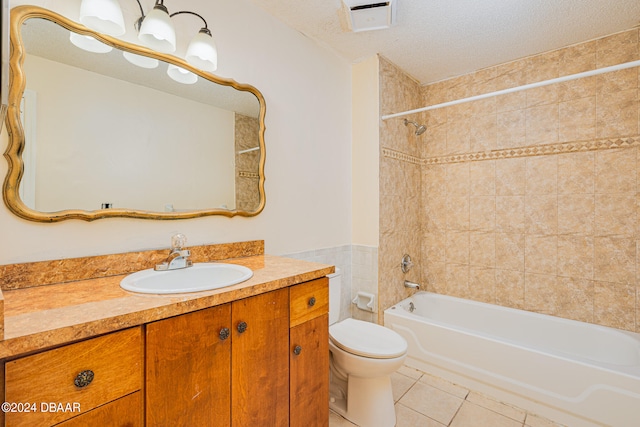 full bathroom featuring tile patterned flooring, a textured ceiling, vanity, toilet, and tiled shower / bath combo