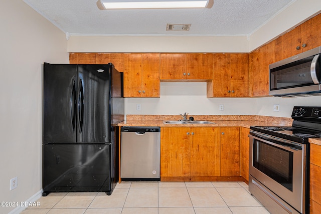 kitchen featuring stainless steel appliances, a textured ceiling, sink, and light tile patterned floors