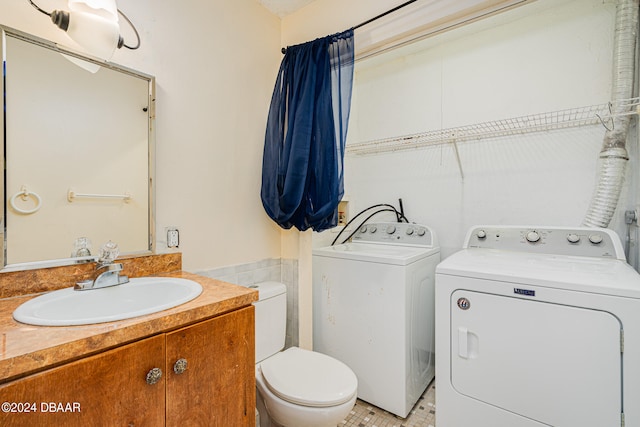 bathroom featuring washing machine and clothes dryer, vanity, and toilet