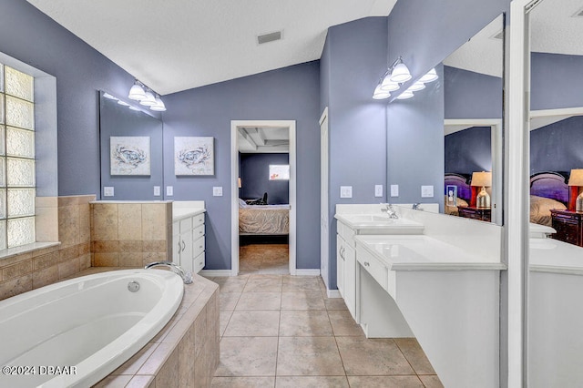 bathroom with vaulted ceiling, tile patterned floors, vanity, and a relaxing tiled tub