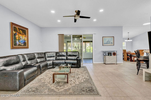 tiled living room with ceiling fan with notable chandelier