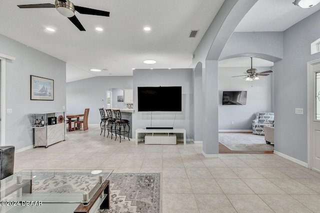 tiled living room with ceiling fan and lofted ceiling