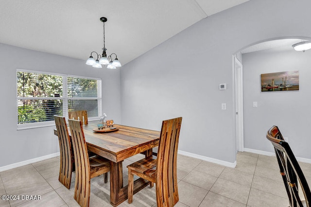 tiled dining space with lofted ceiling and a notable chandelier