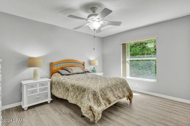 bedroom with ceiling fan, a textured ceiling, and light wood-type flooring