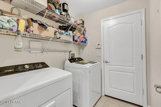 washroom featuring a textured ceiling, light tile patterned floors, and independent washer and dryer